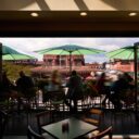 View from indoor seating out to a rooftop patio with green umbrellas overlooking the ByWard Market and city rooftops.