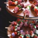 Tiered catering display with meatballs, and antipasto skewers of salami, mozzarella, tomato, and basil.
