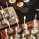 Tiered catering display with deviled eggs, glazed meatballs on skewers.