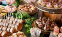 Assorted canapés spread featuring shrimp cocktail, melted cheese sliders, and roast beef tartlets on tiered stands.